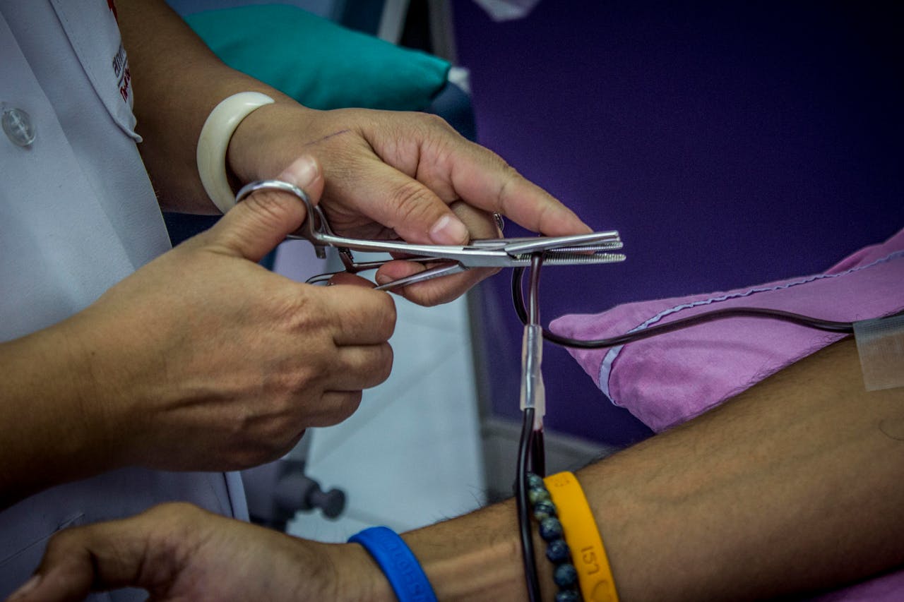 Detailed close-up of hands managing IV clamp during medical procedure in hospital setting.