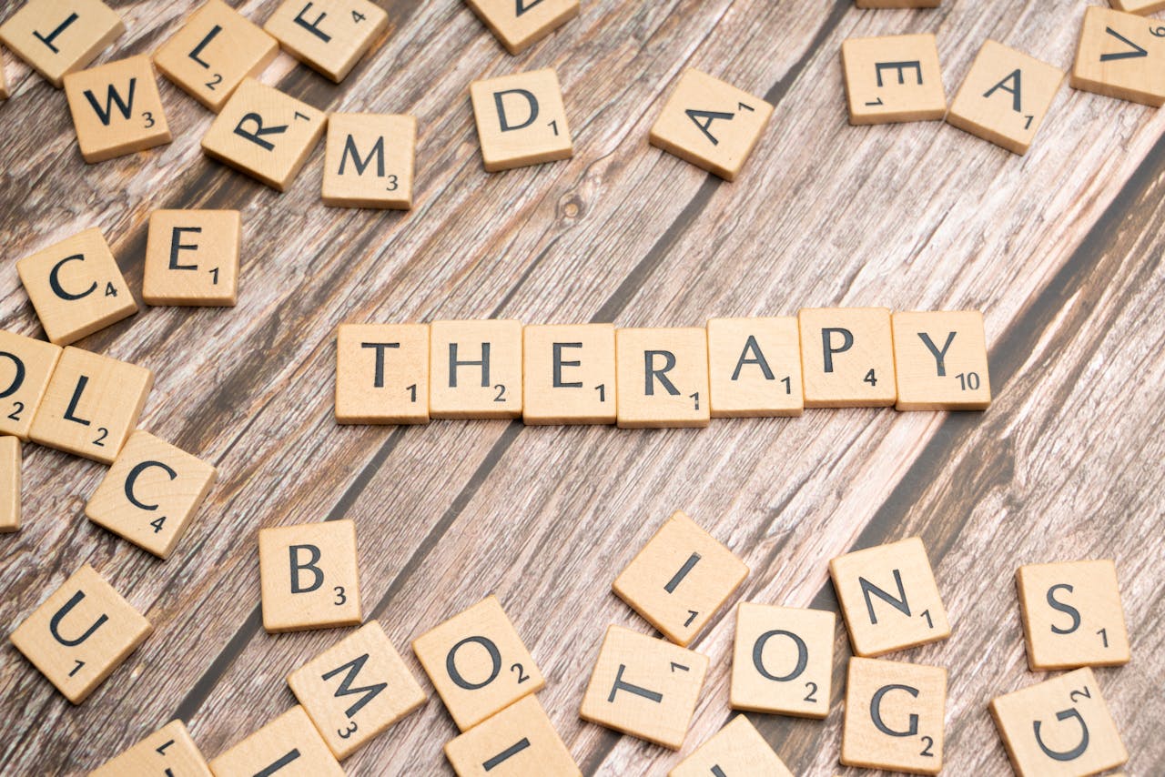 Wooden letter tiles spelling 'therapy' on a wooden background, emphasizing mental health.