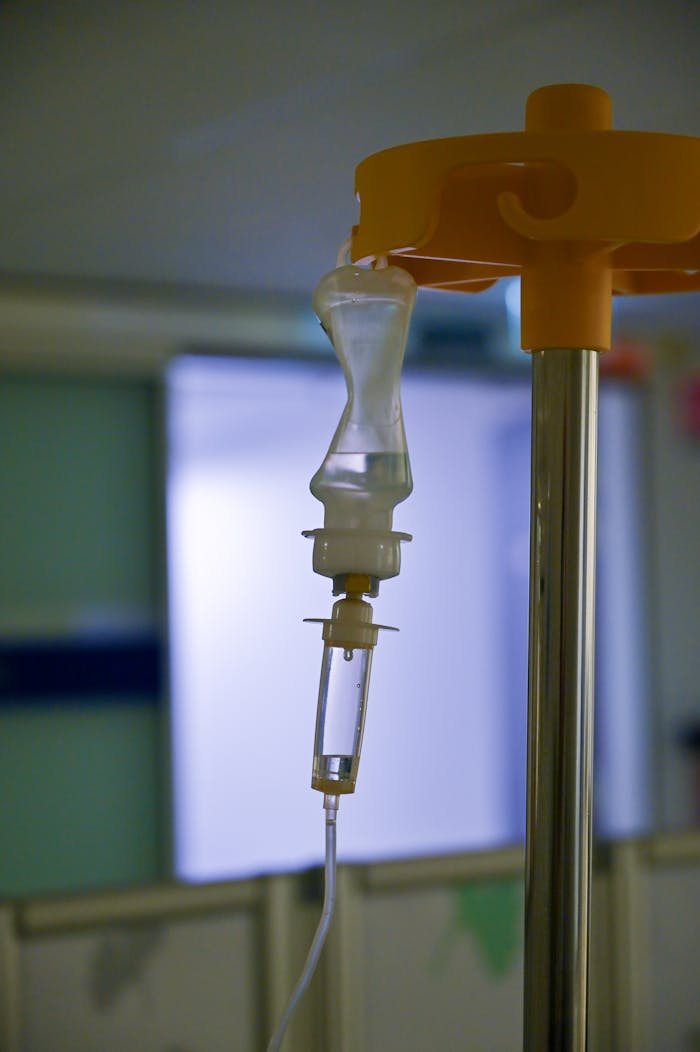 Close-up image of an intravenous drip with blurred hospital background, highlighting medical equipment in use.