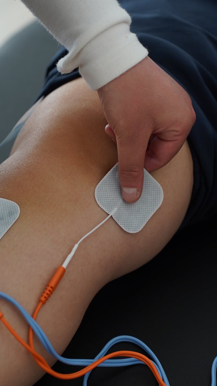 journey Close-up view of a person using electrical stimulation pads on the knee for therapy.